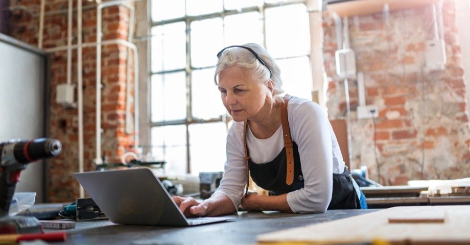 Older woman in an apron looking at a laptop 