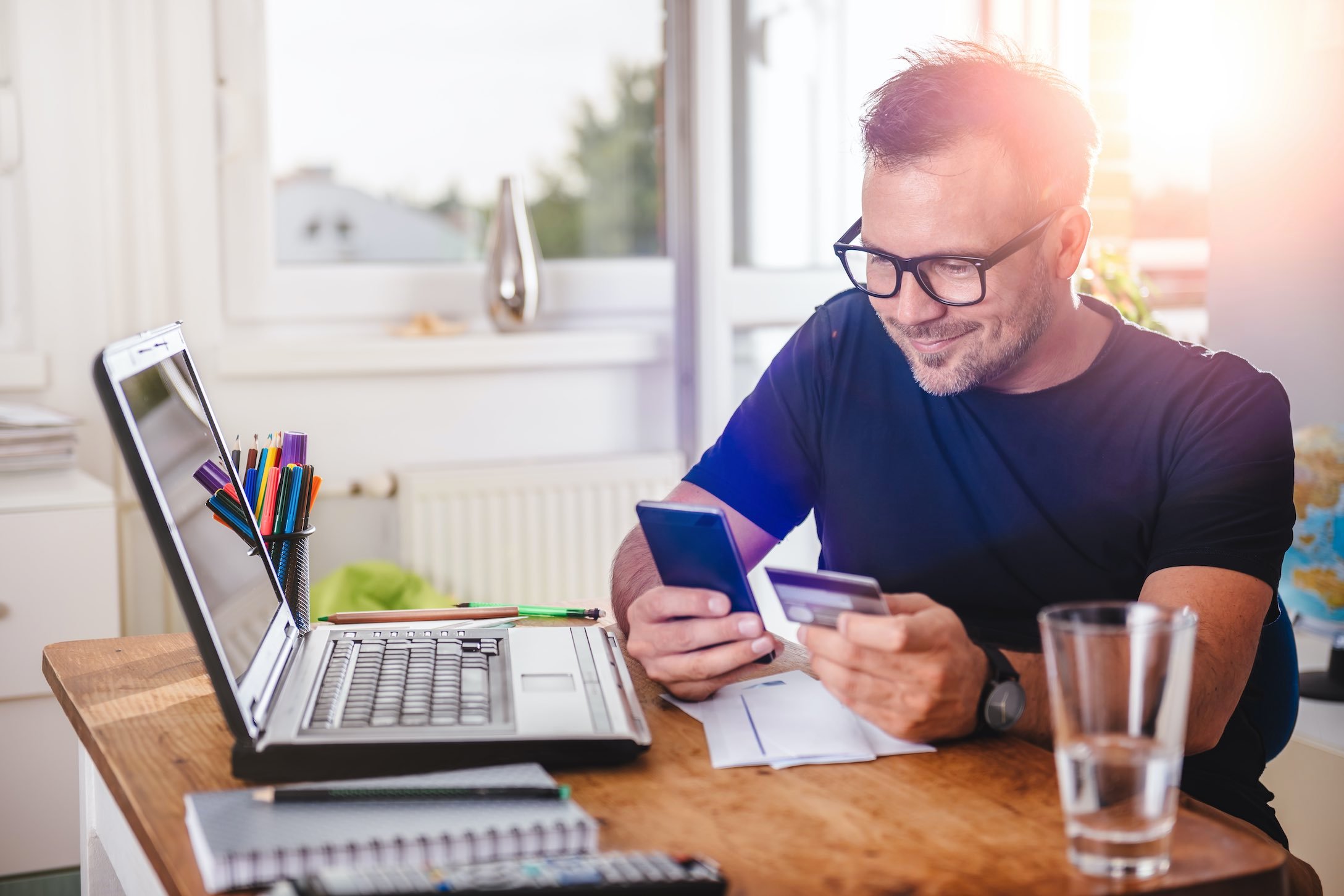 Man looking at card information on phone and laptop